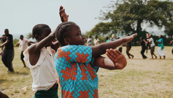 Participants laugh as they dance together outside their War Child supported school in Uganda.