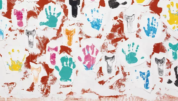 Multicoloured painted hand prints on red background.