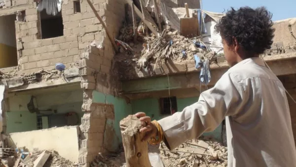 A child looking at a destroyed home in Yemen. 