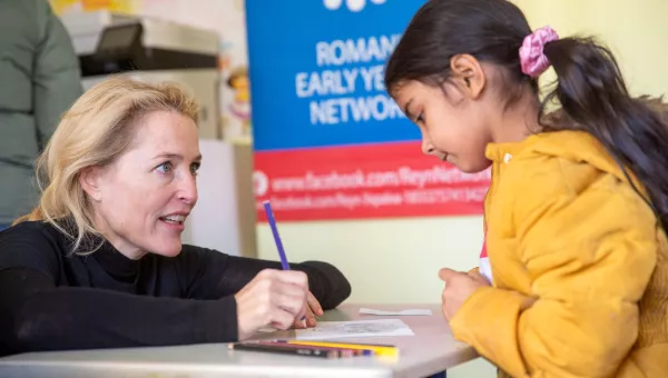 Gillian Anderson with a young child helping a child in a school in Ukraine