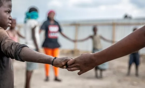 Participants hold hands in a circle as they play games at a War Child centre.