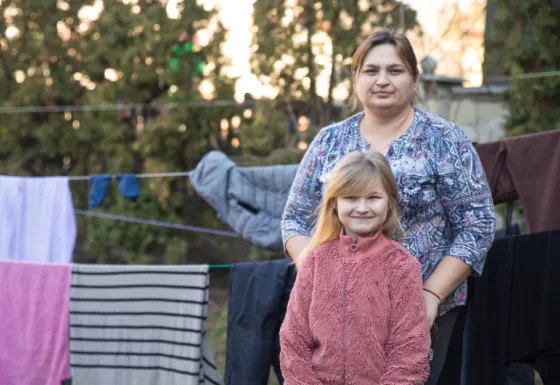 Mother and daughter Maria and Ivanna look to camera standing near a washing line in Ukraine