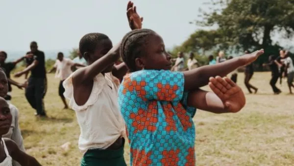 Participants dance outside their school in Uganda.