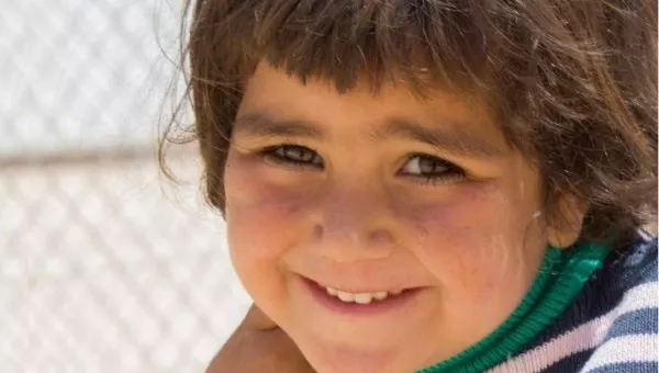 Participant smiles to the camera in a camp for those displaced by conflict.