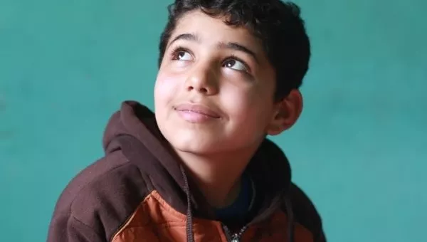 Boy smiling as he completes his school work.