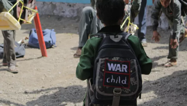 Child in Yemen wears a War Child rucksack outside their school.