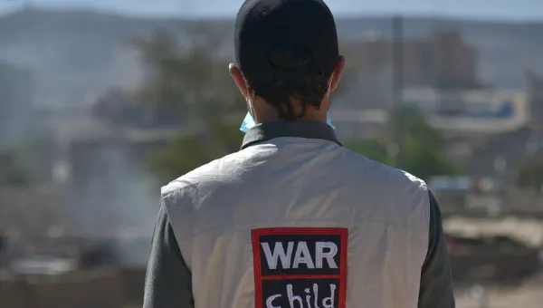 War Child staff member stands with back to camera so we can see their jacket with logo on back.
