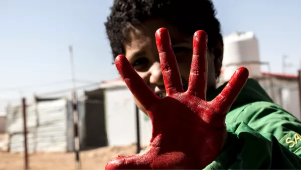 Child with their hand painted red as part of War Child activities to mark Red Hand Day, also known as the International Day against the Use of Child Soldiers.
