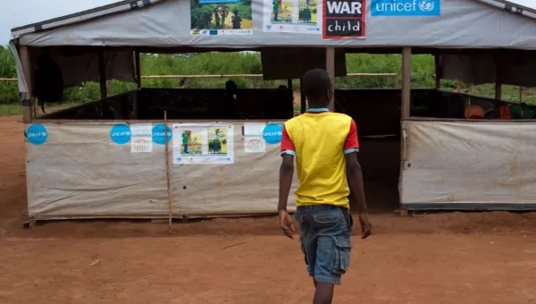 Participant Frederique walks into a War Child centre in the CAR with his back to the camera.