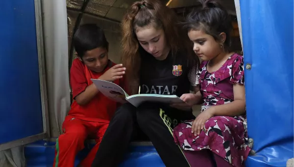 Participant Nadia reads to her siblings at home.