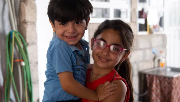 Participant Soleen carries her younger brother in their home.