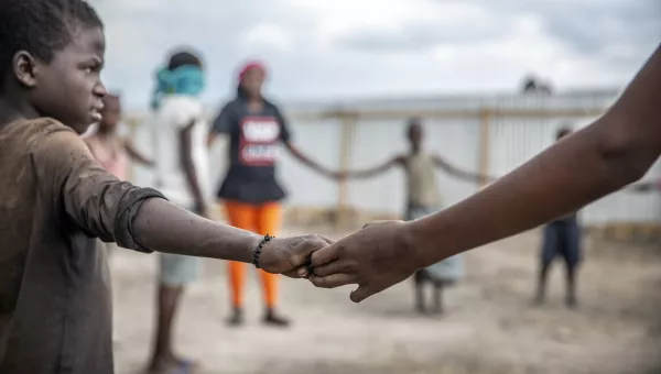 Participants hold hands in a circle as they do activities at a War Child centre.