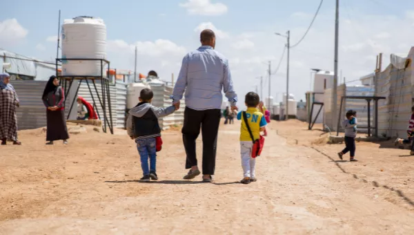 A father walks down the road in the camp where he lives with his family in Iraq.