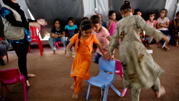 Little girls play musical chairs in a child-friendly space in Iraq.