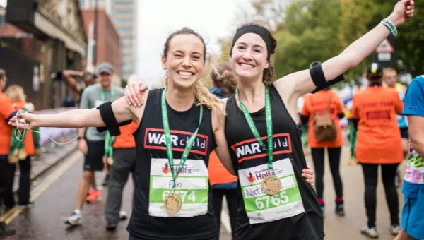 Runners smile to the camera after completing Royal Parks Half Marathon for War Child.