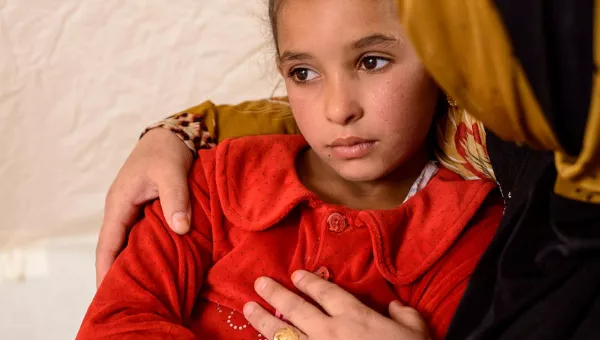 Iraqi girl sits in her mother arms.