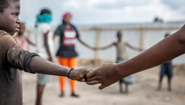 Participants hold hands in a circle as they play games at a War Child centre.