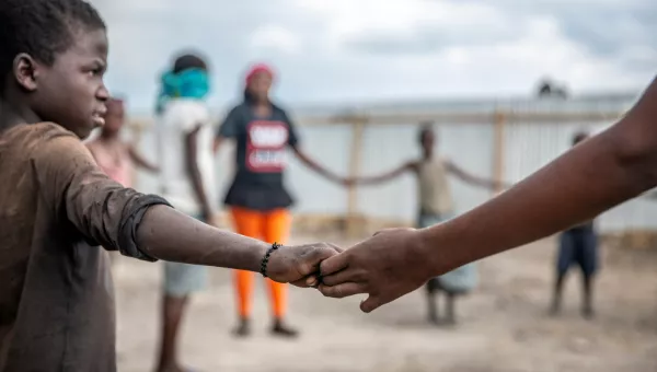 Participants hold hands in a circle as they complete activities at a War Child centre in the Democratic Republic of Congo.