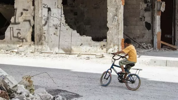 Syrian boy cycles around the city which has been destroyed by conflict.