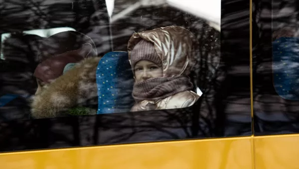 Little girl looking out of the window of the bus taking her to the safe zone.