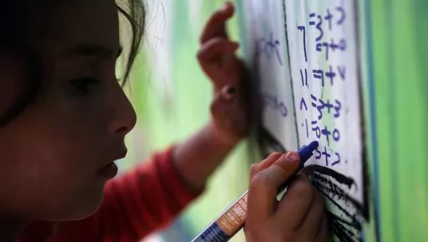 Child writing on a board in a temporary learning space.