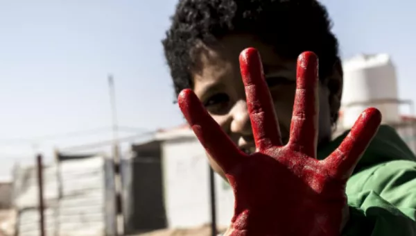 A boy with his hand painted red for Red Hand Day.