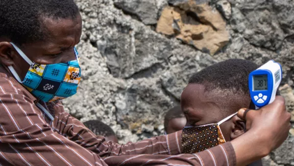 A man helping a boy put his mask on. 