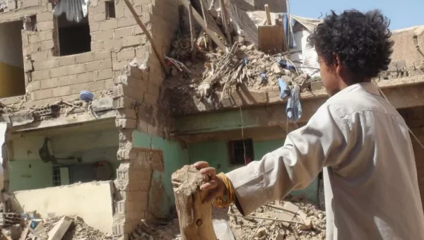A child looking at a destroyed home in Yemen.