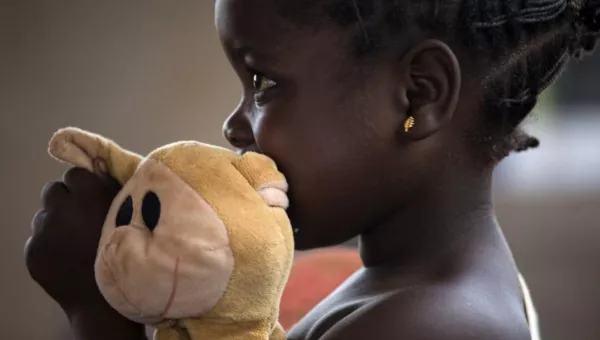 Little girl in the Central African Republic hugs a teddy bear in early childhood development centre.