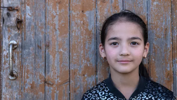Galina aged 8 in Moldova posing against a wooden door