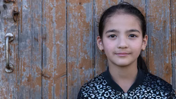 Galina aged 8 in Moldova posing against a wooden door