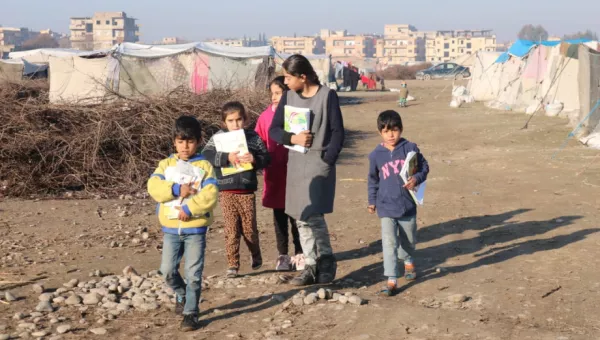Children walking through a refugee camp, Syria. 
