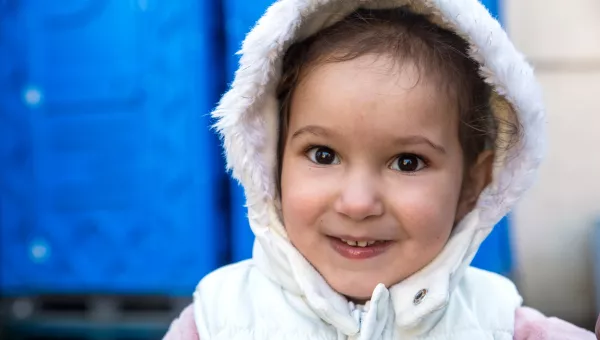 Girl outside in Ukraine smiling in her coat with hood up
