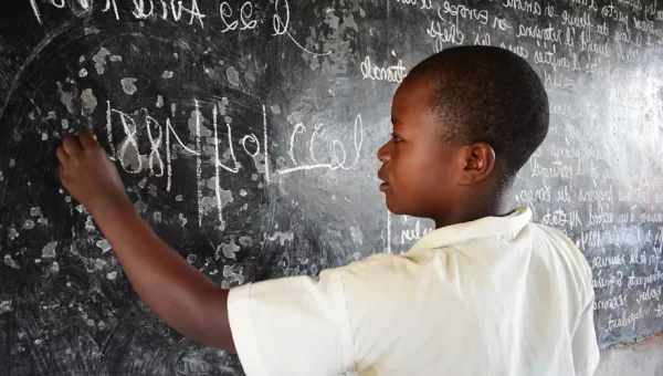 Child drawing on a chalk board in DRC.