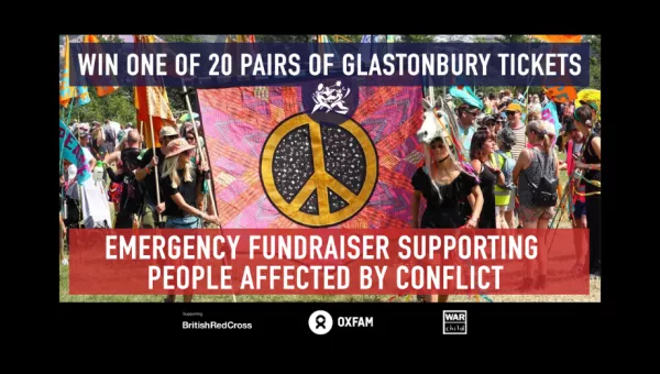 A banner with a peace sign being carried at a parade at Glastonbury