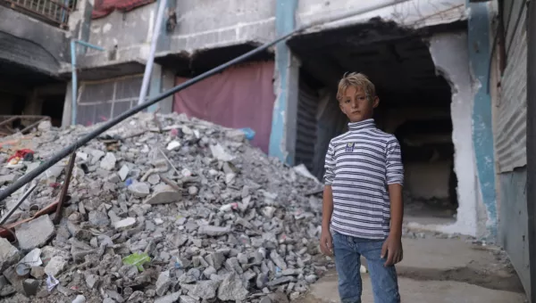 Boy standing next to a collapsed building in Gaza.