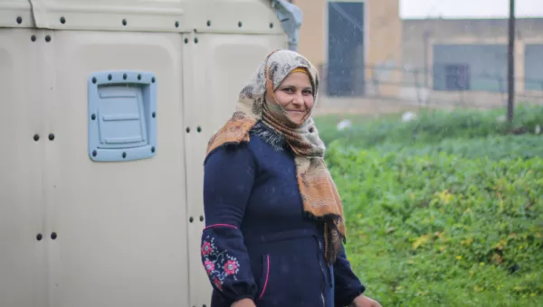 Raina standing in front of a temporary home in Syria.