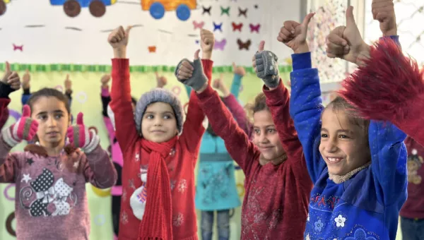 Children smiling and holding thumbs up.