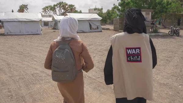 A War Child staff memebr and child walking together.