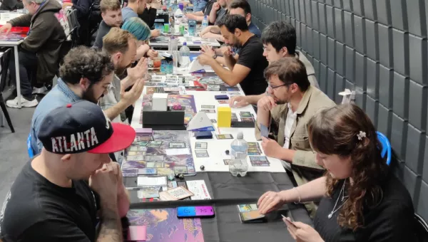 People sitting at a table playing Magic the Gathering.
