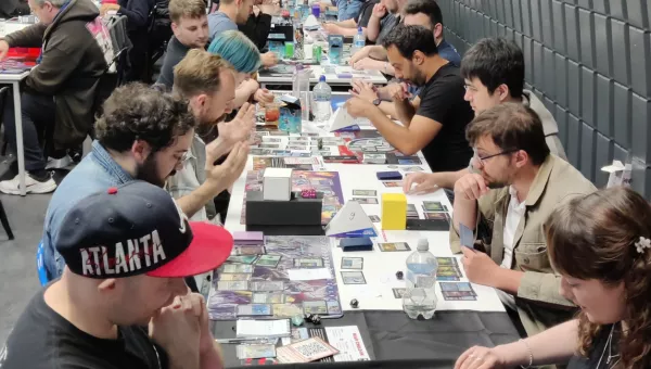 People sitting at a table playing Magic the Gathering.