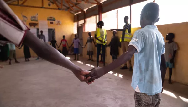 A group of children standing in a circle and holding hands.