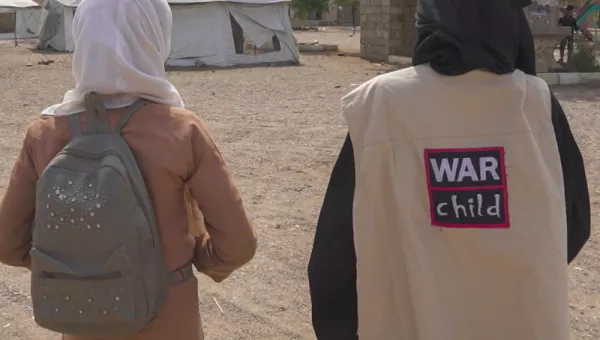 A War Child staff member and a child walking together. 