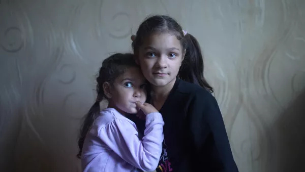 two sisters looking at the camera, one leaning into the other