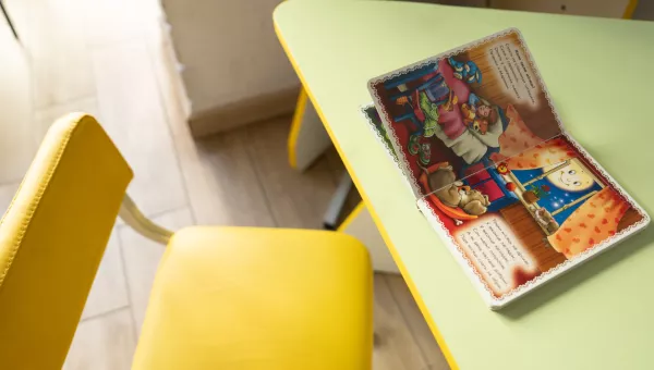 A book on a table with a childs chair.