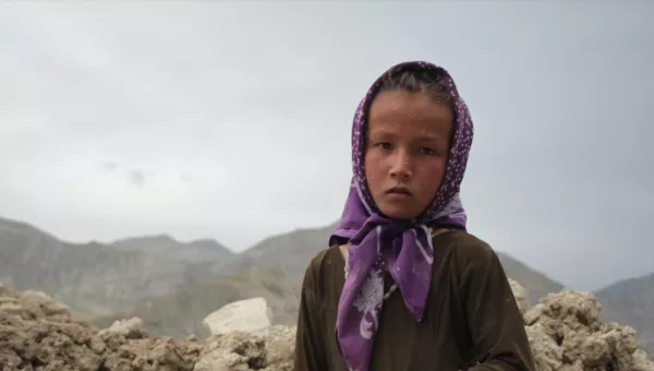 girl looking into camera in front of rubble