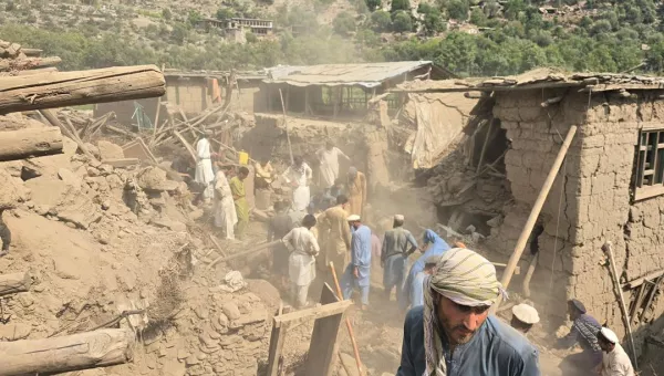 Afghan men surrounded by destroyed houses and rubble.