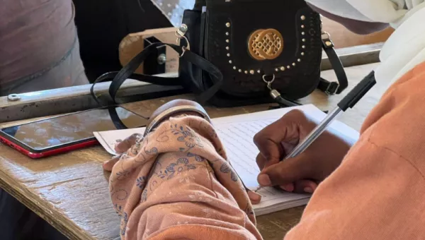 Child's hand holding a pen over a piece of paper with words.