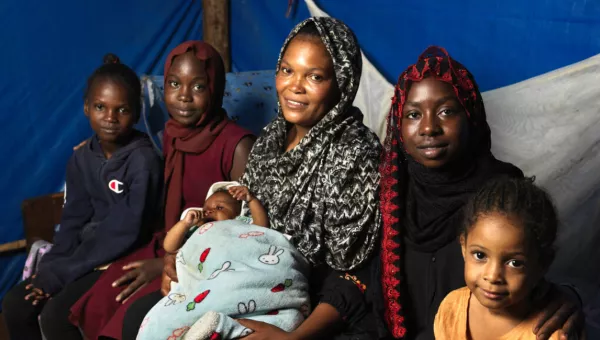 Women and their children sitting in a tent.