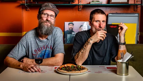 Sleaford Mods members drinking wine and eating pizza